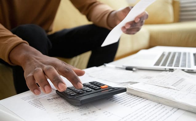 Un homme faisant des calculs avec sa calculette pour mener intelligement son budget
