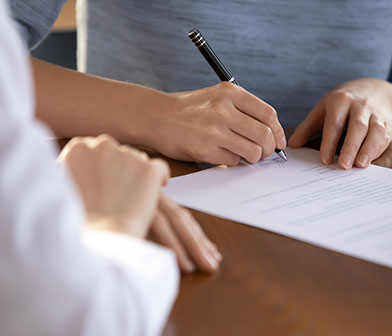 Une personne signant un document et son conseiller qui patiente à côté